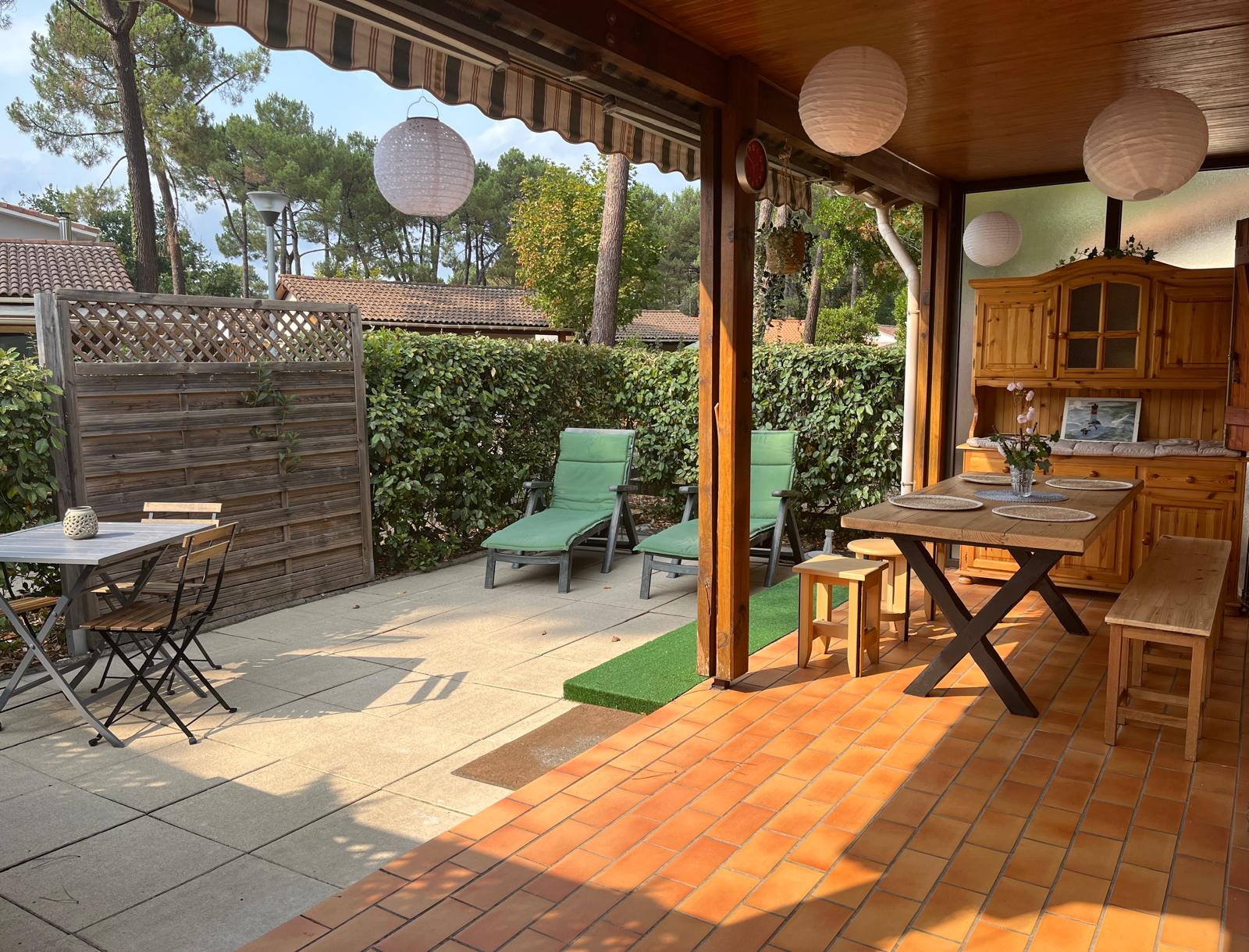 Terrasse couverte avec transats et table de repas